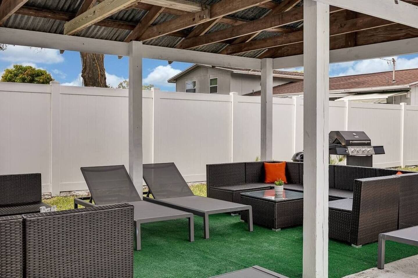 An outdoor patio with wicker furniture, a grill, and a green artificial turf.
