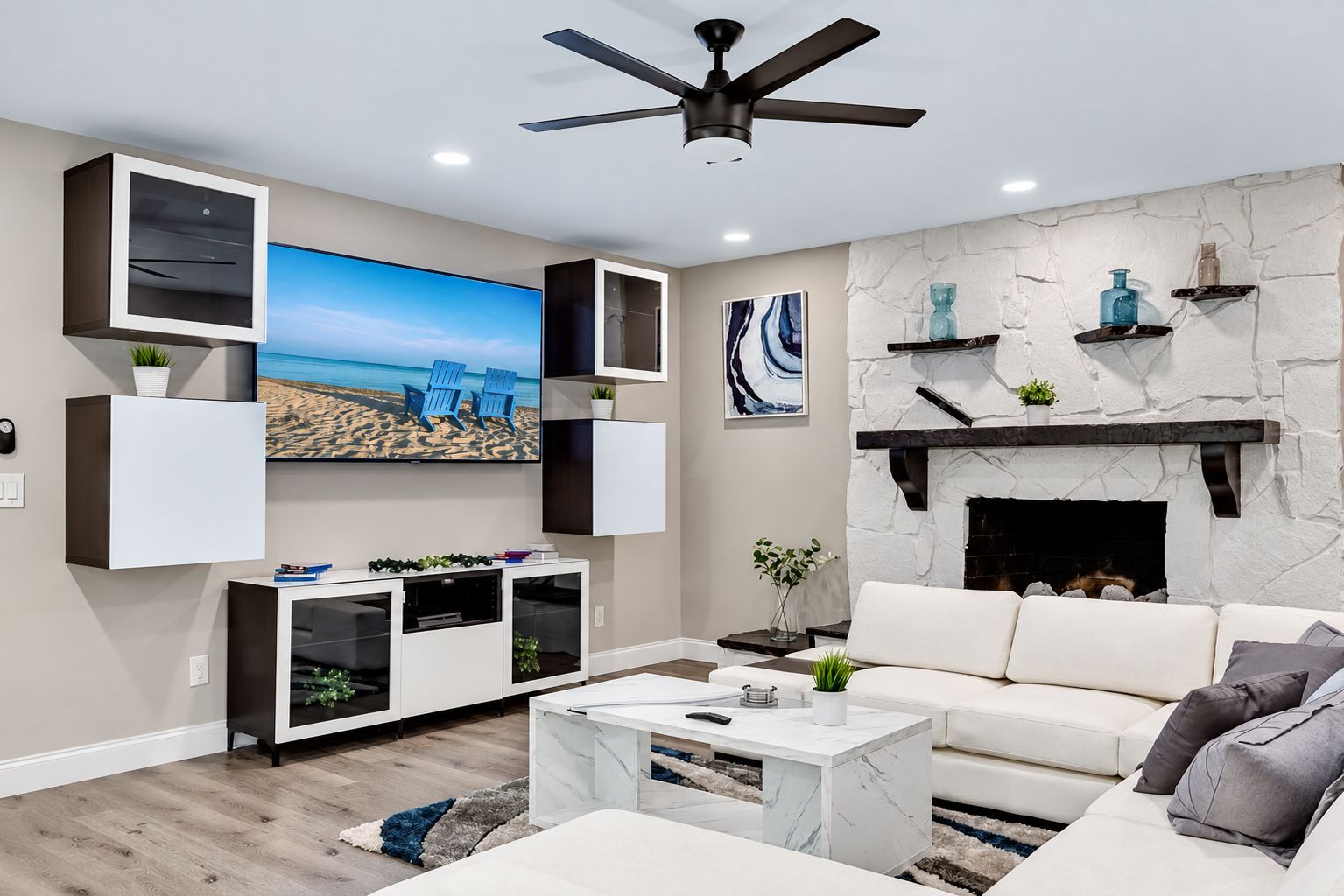 A modern living room with a flat-screen TV, built-in shelving, a fireplace, and a ceiling fan.