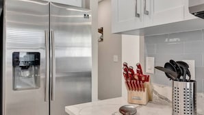 A modern kitchen with stainless steel appliances, a marble countertop, and a knife block. - Heated Pool & Game Room, Sleeps 14 | 10 Min to Tampa Airport & Stadium (Tampa)
