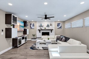 A modern living room with a fireplace, white sofas, a coffee table, and a TV mounted on the wall.