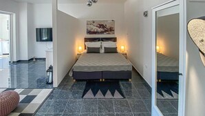 A modern bedroom with a large bed, two bedside lamps, a flat-screen TV mounted on the wall, and a large mirror. - Amazing home in Rukavac (Rukavac)