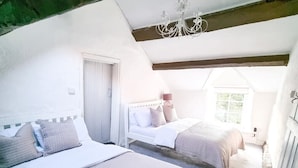 A bedroom with two beds, a chandelier, and a view of the outdoors.