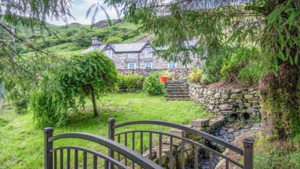 A stone house with a wooden deck and a stone wall.