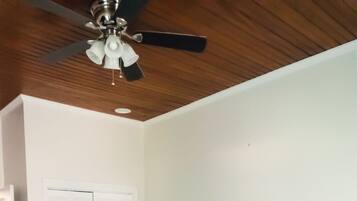 A bedroom with a bed, a ceiling fan, a wardrobe, and a nightstand.