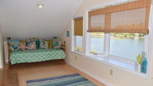 Ein Schlafzimmer mit einem Bett, einem Fenster mit Seeblick und einem Streifenmuster-Teppich.