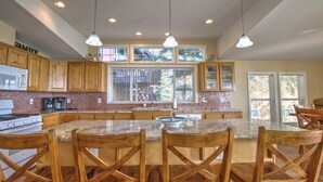 A spacious kitchen with wooden cabinets, a granite countertop, and a large island with bar stools. - Deja Blue Lakehouse - Lake Front Property. The perfect vacation spot! (Garden City)