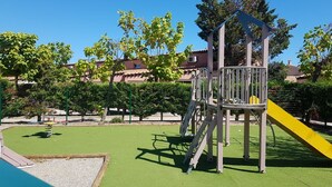 A playground with a climbing structure and a slide, surrounded by green grass and trees. - Villa in secure residence with swimming pool 200m from the beach (Saint-Cyprien)