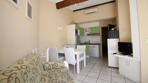 A compact living space with a sofa, dining table, and kitchenette. - Villa in secure residence with swimming pool 200m from the beach (Saint-Cyprien)