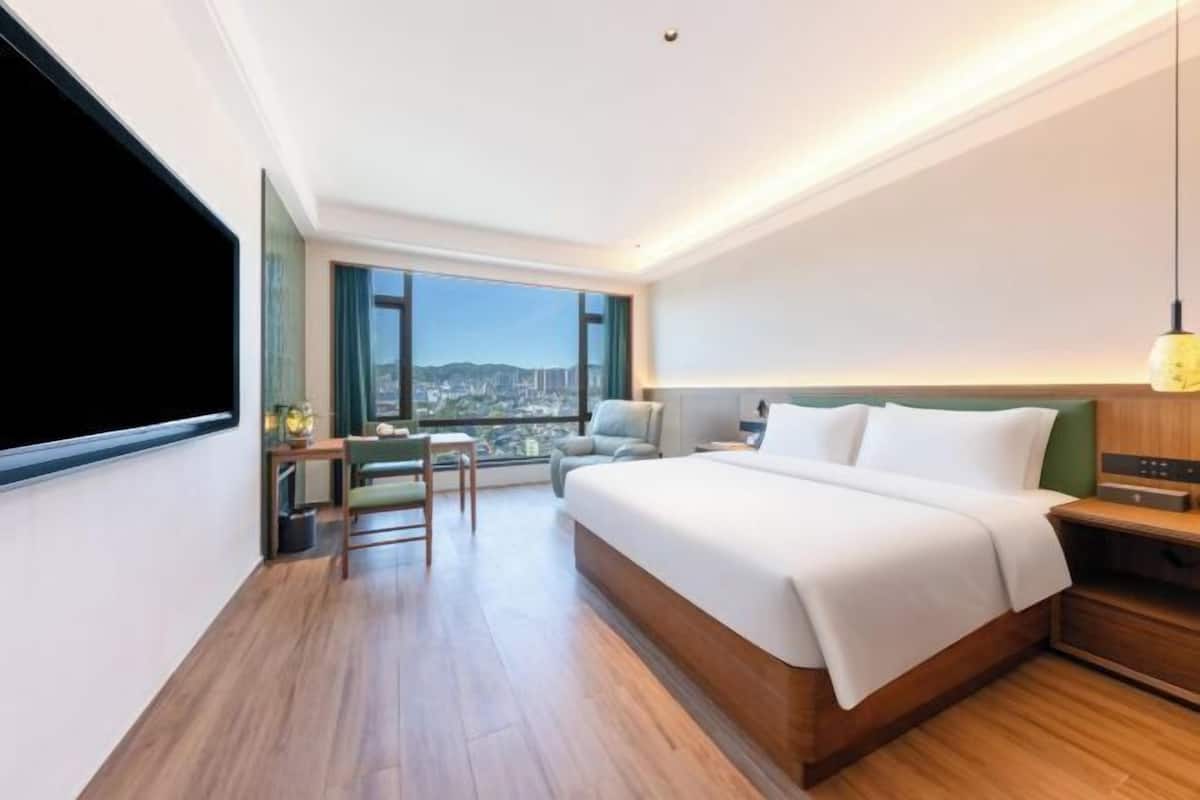 Una habitación de hotel moderna con una cama grande, un escritorio y vistas a la ciudad.