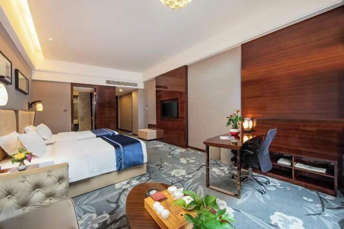 Una habitación de hotel con cama, escritorio, silla, mesita de centro y televisor.