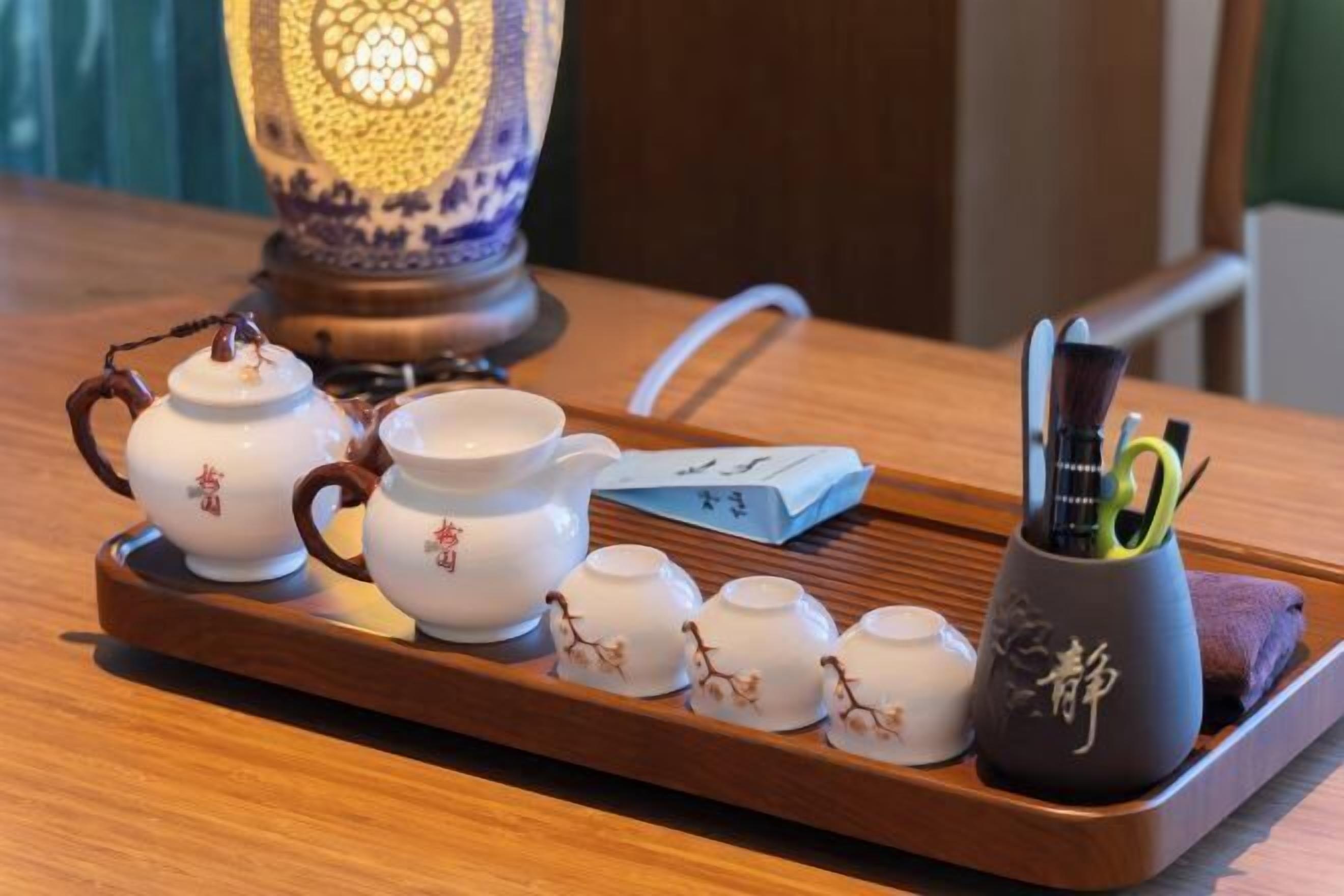 A tray with teapots, cups, and a teapot with a green handle.
