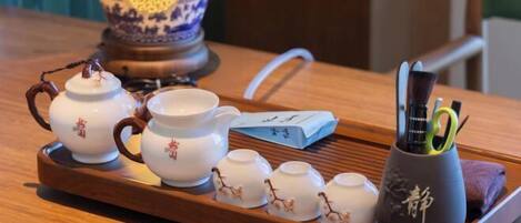 A tray with teapots, cups, and a teapot with a green handle.