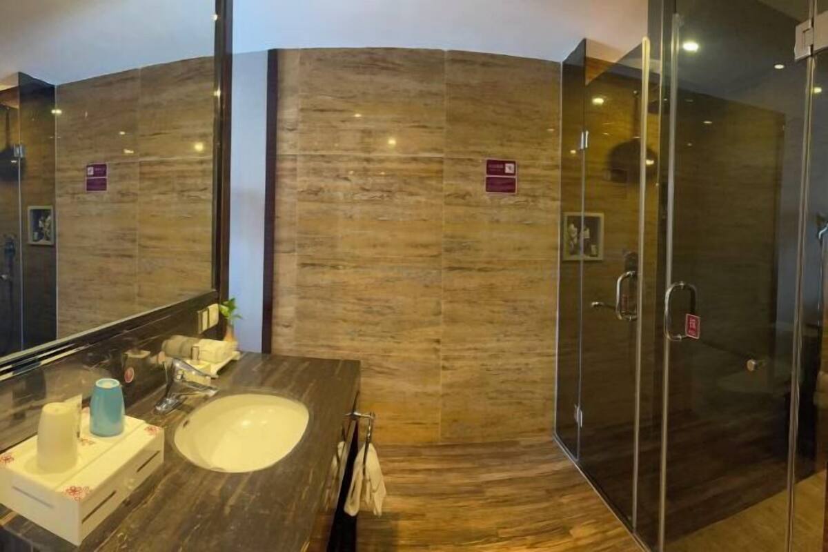 Bathroom features a large mirror, sink, glass-enclosed shower, toilet, and bidet.