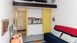 A compact room with a bed, a small kitchenette, and a door leading to another room. - VIVA Casinha da Foz - Close to the beach (Porto)