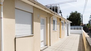A row of beige buildings with closed shutters, a tiled walkway, and a construction crane in the background. - VIVA Casinha da Foz - Close to the beach (Porto)