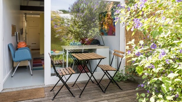 An outdoor patio with a table and chairs, a blue chair, and a wooden deck. - VIVA Casinha da Foz - Close to the beach (Porto)