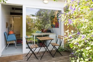 An outdoor patio with a table and chairs, a blue chair, and a wooden deck.