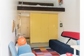 Ein gemütlicher Raum mit einem Bett, einer Schlafcouch, einem gelben Kleiderschrank und einem kleinen Tisch.
