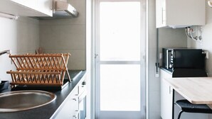 Una cucina compatta con lavello, stendibiancheria in legno e forno a microonde.
