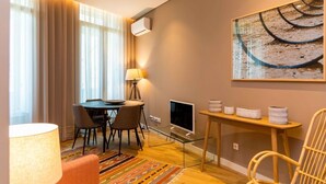 Ein modernes Wohnzimmer mit Essbereich, einem Flachbildfernseher, einer Lampe und einem Gemälde an der Wand.