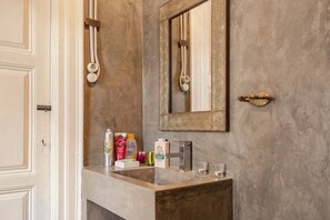 Une salle de bain avec un lavabo en marbre, un miroir doté d’un cadre décoratif et des articles de toilette posés sur le comptoir.