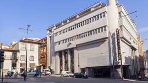 Un edificio de varios pisos con una destacada torre cilíndrica, grandes ventanales y un estilo arquitectónico clásico.