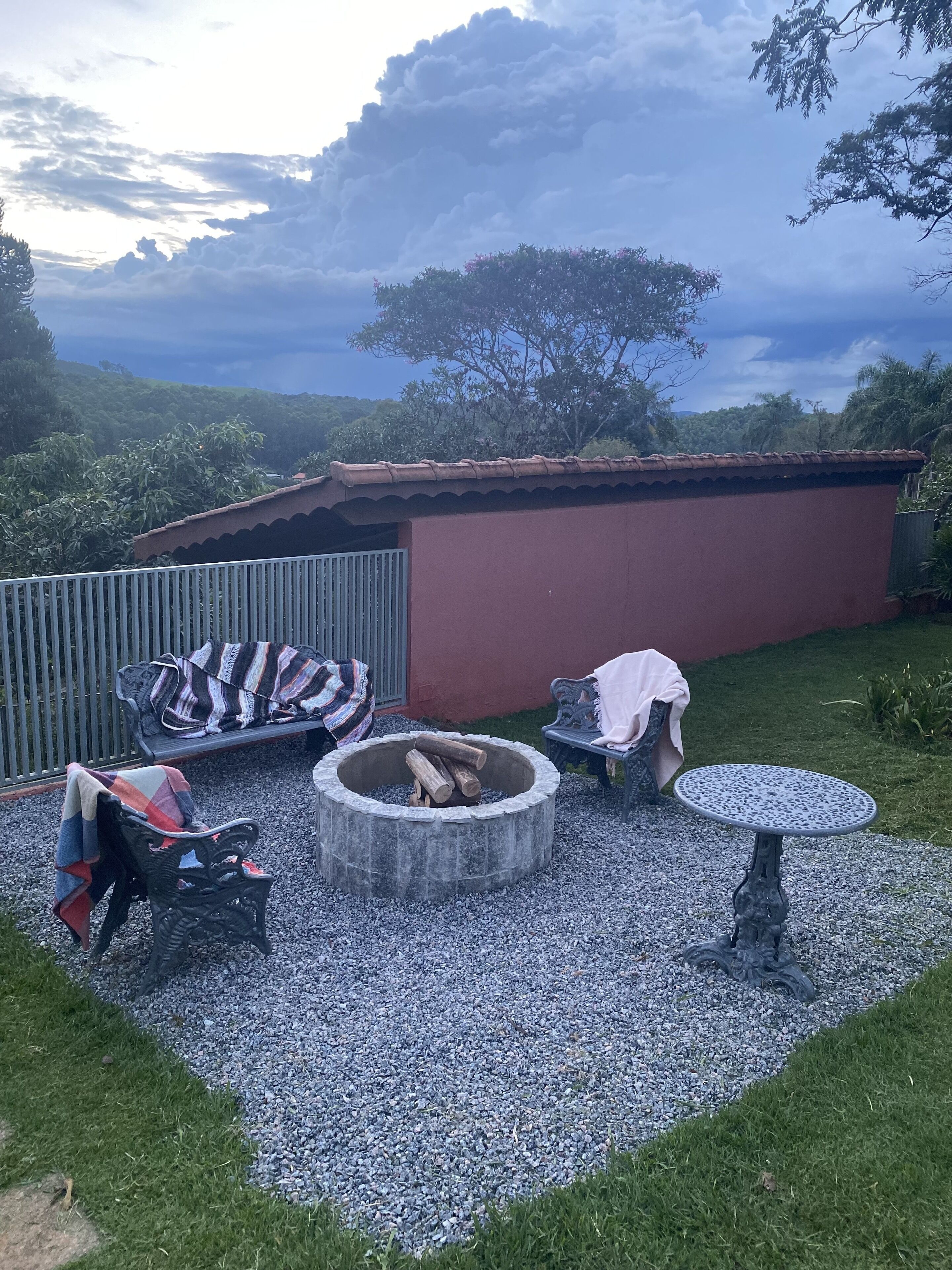 A backyard with a fire pit, a bench, and a table.