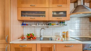 A kitchen with wooden cabinets, a stainless steel sink, and a variety of kitchen items on the countertop. - Beach front home in Jesenice (Jesenice)