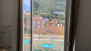 Un balcon avec une table et des chaises, un canapé et une vue sur une colline parsemée de bâtiments.