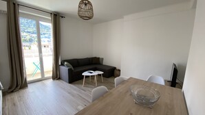 Un salon moderne avec une table à manger en bois, un canapé et une grande fenêtre agrémentée de rideaux.