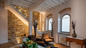 Una sala de estar acogedora con una pared de piedra, una escalera y vistas al exterior a través de una ventana.