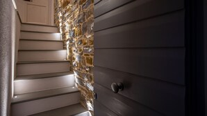 Una escalera con un muro de piedra a un lado y una puerta de madera oscura al otro.