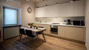 Una cocina moderna con gabinetes blancos, estufa a gas, microondas y comedor con mesa y sillas.