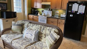 A cozy living room with a wicker sofa, wooden cabinets, and a black refrigerator. - Garth Newell Waterfront -  Kayaks, canoes, water trampoline, fire pit, swimming (Maryland)
