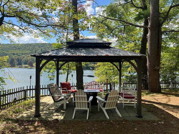 Un belvédère abritant une table et des chaises, d’où l’on a vue sur un lac.