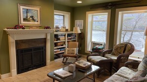 A cozy living room with a fireplace, wicker furniture, and a bookshelf. - Garth Newell Waterfront -  Kayaks, canoes, water trampoline, fire pit, swimming (Maryland)