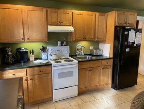 Fully equipped kitchen with a stove, coffee maker, toaster, sink, and kettle.
