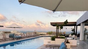 A poolside area with lounge chairs and umbrellas, a clear view of the sky, and a modern architectural design. - Awesome Location for 5th AVE & BEACH access without  noise! INCREDIBLE ROOFTOP (Playa Del Carmen, Solidaridad)