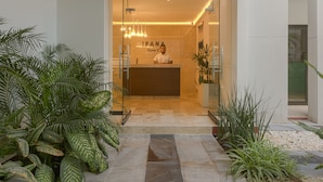 A reception area with a modern design, featuring a receptionist desk, glass doors, and indoor plants. - Awesome Location for 5th AVE & BEACH access without  noise! INCREDIBLE ROOFTOP (Playa Del Carmen, Solidaridad)