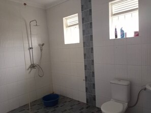A bathroom with a shower, toilet, and two windows. - Welcome to a beautiful place ~ KareBer Abode (Gulu)