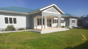 Une maison moderne à deux étages, dotée d’un porche abrité, d’une pelouse bien entretenue et surplombée d’un ciel bleu dégagé.