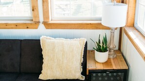 Una habitación acogedora con un sofá oscuro, una mesita con una lámpara y una planta en maceta.