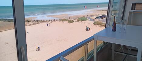 Ein Balkon mit Blick auf einen Sandstrand und das Meer.