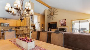 Un salon chaleureux avec une table à manger en bois, des chaises en osier, un canapé et un lustre.