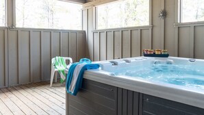 Un bain à remous avec une terrasse en bois, une chaise et une serviette.
