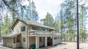 Une cabane à deux étages dotée d’un balcon, entourée de pins.