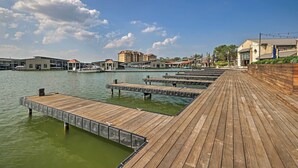 A wooden dock extending into a body of water with buildings in the background. - Modern Townhome w/ Patio, Next Door to Resort (Horseshoe Bay)