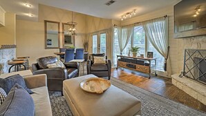 A modern living room with a fireplace, leather furniture, and a dining area with a table and chairs. - Modern Townhome w/ Patio, Next Door to Resort (Horseshoe Bay)
