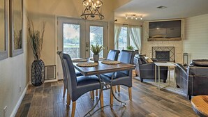 A dining area with a wooden table and chairs, a chandelier, and a fireplace in the background. - Modern Townhome w/ Patio, Next Door to Resort (Horseshoe Bay)
