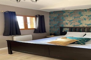 Een slaapkamer met een bed, gordijnen, een raam en een bloemendecor op de muur.